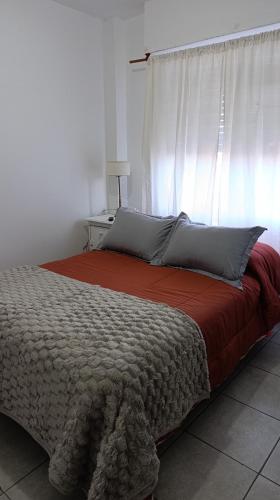 a bedroom with a bed with a red blanket and a window at Altos Jujuy 2 in San Salvador de Jujuy