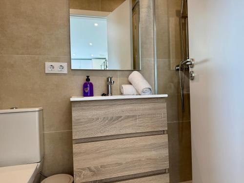 a bathroom with a sink and a toilet and a mirror at Besso Somhome in Peñíscola