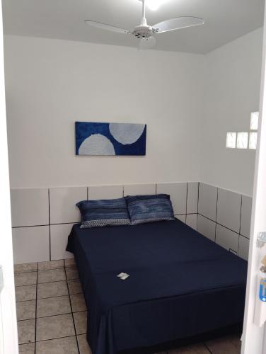 a room with a bed with blue pillows and a ceiling at Casa 55 in Guarapari