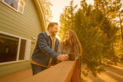 a man and woman standing next to a wooden fence at The Sparrows Nest Cozy Charm Fire Pit Fun in Shaver Lake