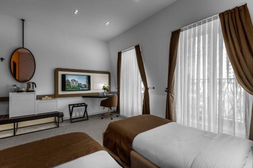 a bedroom with a bed and a desk and a window at Ivy Garden Hotel Baku in Baku