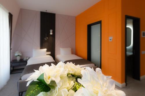 a hotel room with three beds and white flowers at Ivy Garden Hotel Baku in Baku