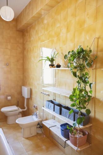 a bathroom with a toilet and plants on the wall at Villino TerrAmare in Reggio di Calabria