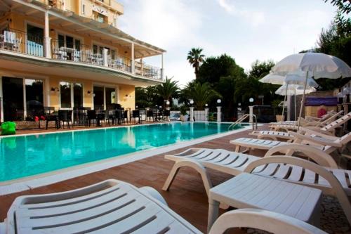 una piscina con sedie a sdraio bianche e un hotel di Hotel Mocambo piscina e spiaggia a San Benedetto del Tronto