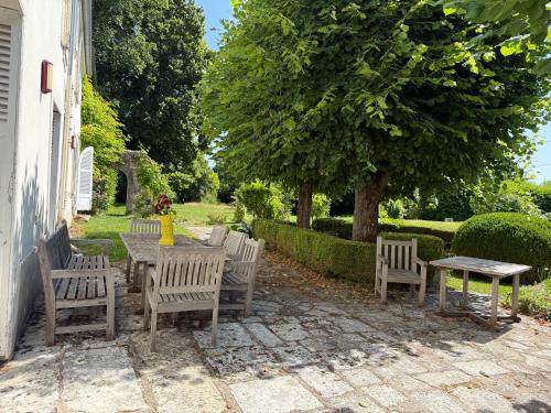 Un patio con una mesa y sillas y un árbol. en Le Manoir de la Seine - proche Giverny, en Bennecourt
