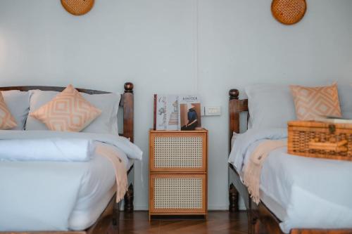 a bedroom with two beds and a nightstand between them at ภูตะวัน-บ้านท่าจัน ม่อนแจ่ม in Mon Jam