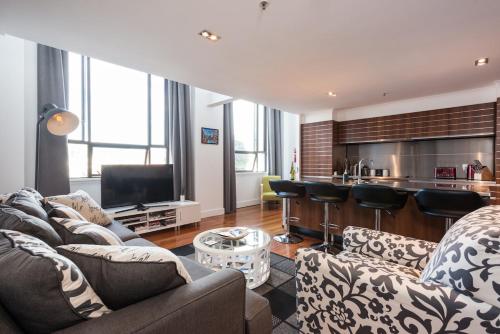 a living room with two couches and a kitchen at Large Executive Inner City Apartment in Wellington