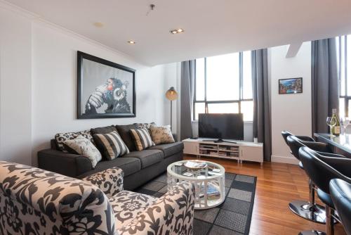 a living room with a couch and a tv at Large Executive Inner City Apartment in Wellington