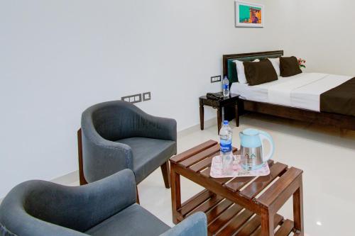 two chairs and a table in a room with a bed at Hotel O Giriraj Palace by Govindam in Jaipur