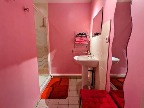 une salle de bain rose avec un lavabo et un miroir dans l'établissement Chambre Coquelicot au calme, nature et authenticité du 18ème avec petit déjeuner inclus - FR-1-589-702, à Moyenmoutier