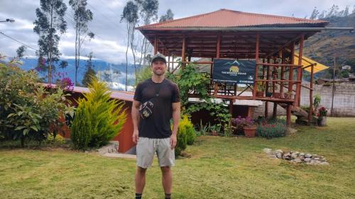 a man is standing in front of a building at the wooden house choquequirao in Cachora