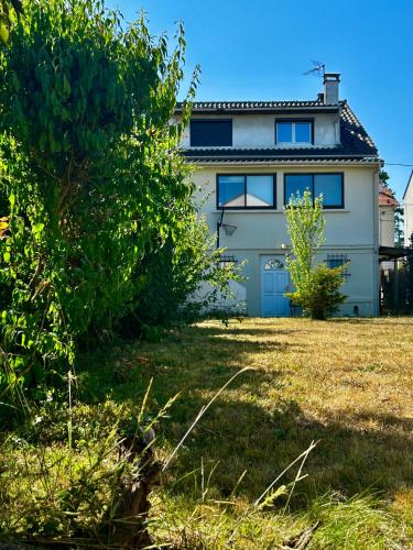 a white house with a blue door and a yard at Villa à 30 min des parcs Asterix et Disneyland in Chelles