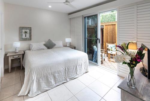 a bedroom with a bed and a table with a vase of flowers at La Bella Waters 3 - Oceanview's, Pool, Buggy and Transfers in Hamilton Island