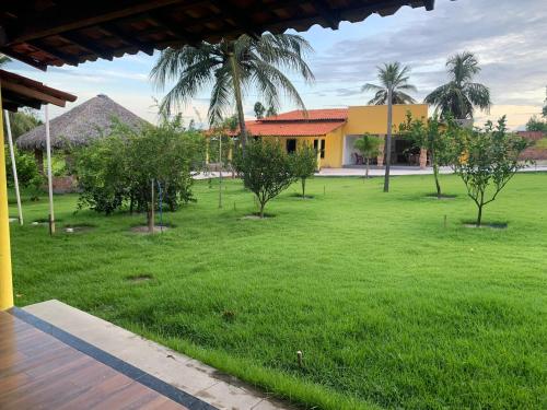 a green yard with a house and palm trees at Chalé Rota Das Dunas in Barreirinhas