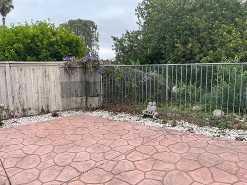 a fence in a yard with a stone patio at Family-Friendly Sunny SD Escape, Sleeps 8, Beach, Zoo, Downtown & Convention Center in San Diego
