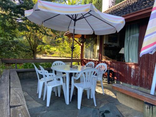 a table and chairs with an umbrella on a porch at Family home with lake access in Villarrica