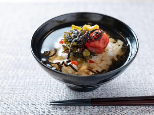 a black bowl of food on a table with chopsticks at Super Hotel JR Shin-Osaka Higashiguchi in Osaka