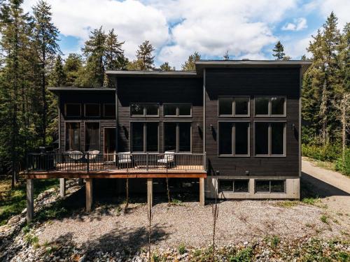 a black house with a porch and a deck at Chalet Ankoay - Relaxation Nature & Private Spa in Saint Come
