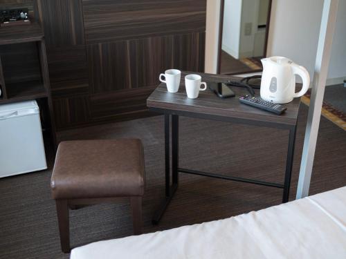 a table with two cups and a chair in a hotel room at Super Hotel JR Shin-Osaka Higashiguchi in Osaka