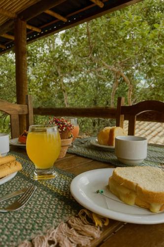 a table with a plate of bread and a glass of orange juice at Pousada Bella Vista in Serra do Cipo