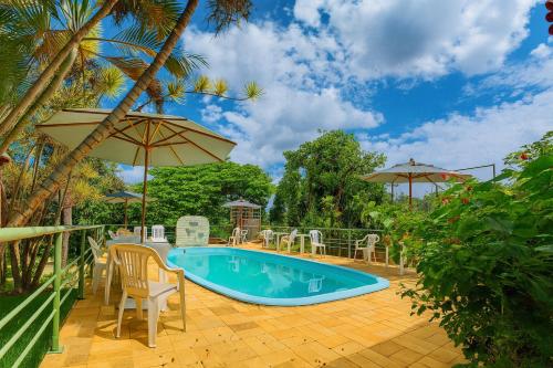 a swimming pool with chairs and an umbrella at Pousada Bella Vista in Serra do Cipo