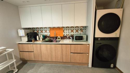 a kitchen with white cabinets and a microwave at Bom Stay in Seoul
