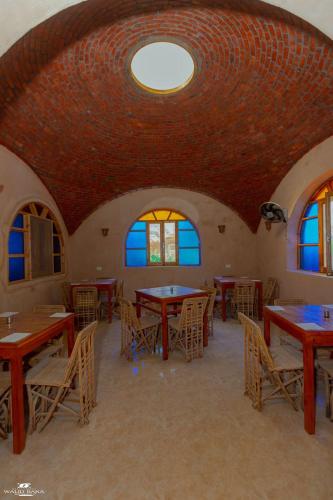 a dining room with tables and chairs and windows at amazing room in siwa oasis in Siwa