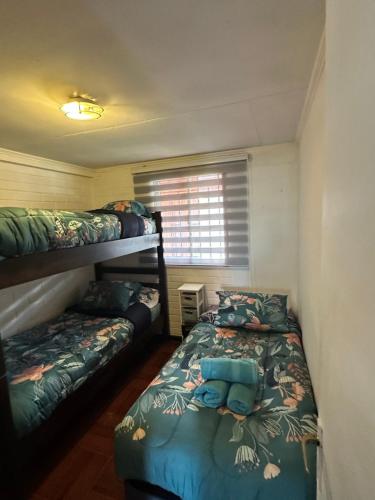 a bedroom with two bunk beds and a window at Casa Hostal Nora, Rauquén Curicó in Curicó