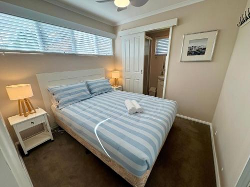 1 dormitorio con 1 cama con edredón de rayas azul y blanco en The Beach Quarters, en Broadwater