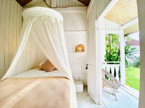 a bedroom with a canopy bed and a window at Villa Stari in Canggu