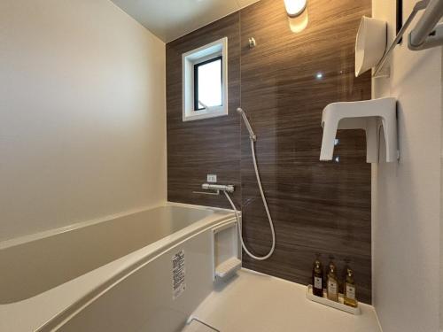 a bathroom with a bath tub and a sink at WinGoodDays in Kumamoto