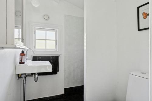 a white bathroom with a sink and a window at Beach And Forest Close To Tisvilde House in Tisvildeleje