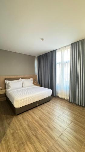 a bedroom with a large bed and a large window at d'primahotel ITC Mangga Dua in Jakarta