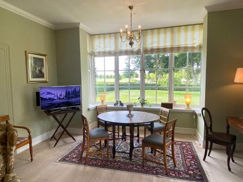ein Esszimmer mit Tisch und Stühlen und einem Fernseher in der Unterkunft Manor House Overlooking Fields And Garden in Ringe