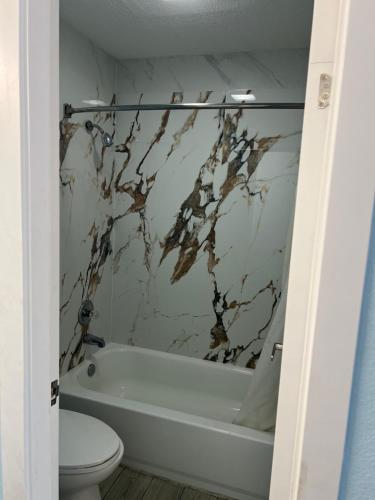 a bathroom with a white tub and a toilet at Crown Inn in Memphis