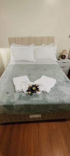 a bed with two towels and flowers on it at Pousada Valle do Sol in Campos do Jordão