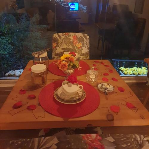 a wooden table with red plates and flowers on it at Pousada Valle do Sol in Campos do Jordão