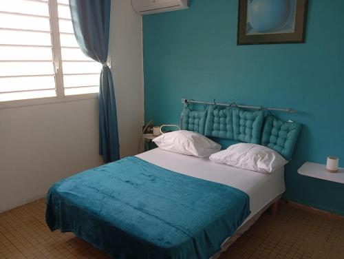 a blue bedroom with a bed with a blue headboard at Villa Ludger-Rose in Le Moule