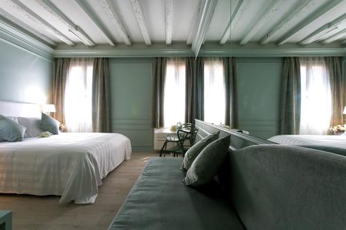 a bedroom with two beds and a couch and windows at Aquamare, boutique b&b in Venice