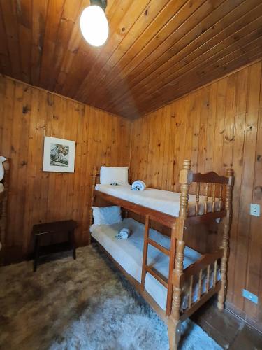 two bunk beds in a room with wooden walls at Chalés Valle do Sol in Campos do Jordão