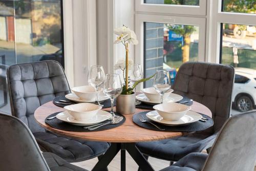 a wooden table with plates and wine glasses on it at New Build in Pilsen Spacious 2 Bed 2 Bath Unit in Chicago