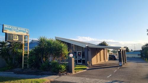 a building with a sign in a parking lot at Pelicans Motel San Remo in San Remo