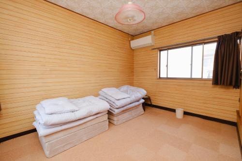 a room with two stools in a room with wooden walls at なまけ者の宿 in Ise