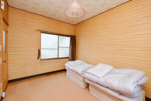 a room with two beds in a room with a window at なまけ者の宿 in Ise