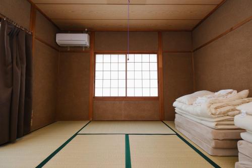 an empty room with a bed and a window at なまけ者の宿 in Ise