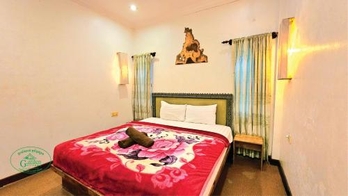 a bedroom with a bed with red sheets and shoes on it at Garden Village Guesthouse & Pool Bar in Siem Reap