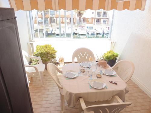 une table blanche avec des chaises blanches et une fenêtre dans l'établissement Joli 2 pièces à 200m des plages avec terrasse et parking - FR-1-338-163, à Sète