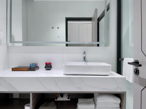 a white bathroom with a sink and a mirror at Shenzhen Shatoujiao Subway Station Apartment Hotel in Shenzhen