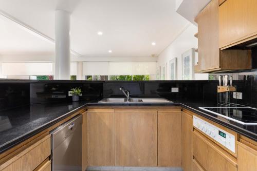 Una cocina con gabinetes de madera y un fregadero. en Mirage Resort Villa 130 with access to Sheraton Facilities, en Port Douglas