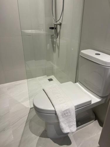 a white bathroom with a toilet and a shower at Bali hotel 